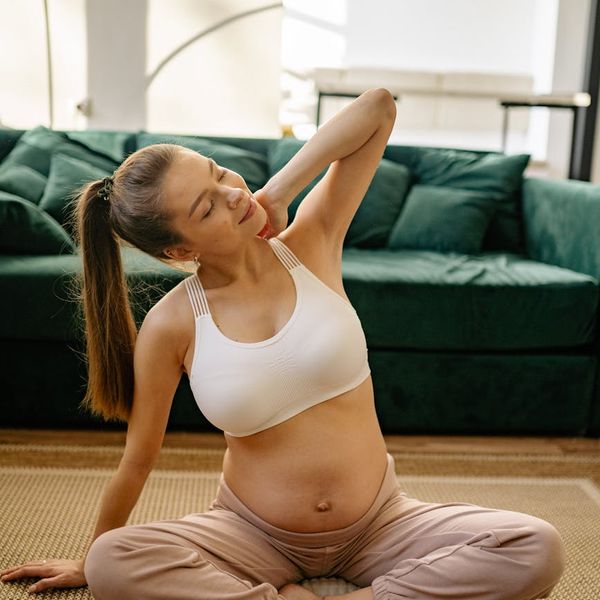 Pregnant woman in a peaceful yoga pose in a calm setting.