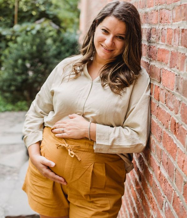 Smiling pregnant woman stretching gently outdoors.